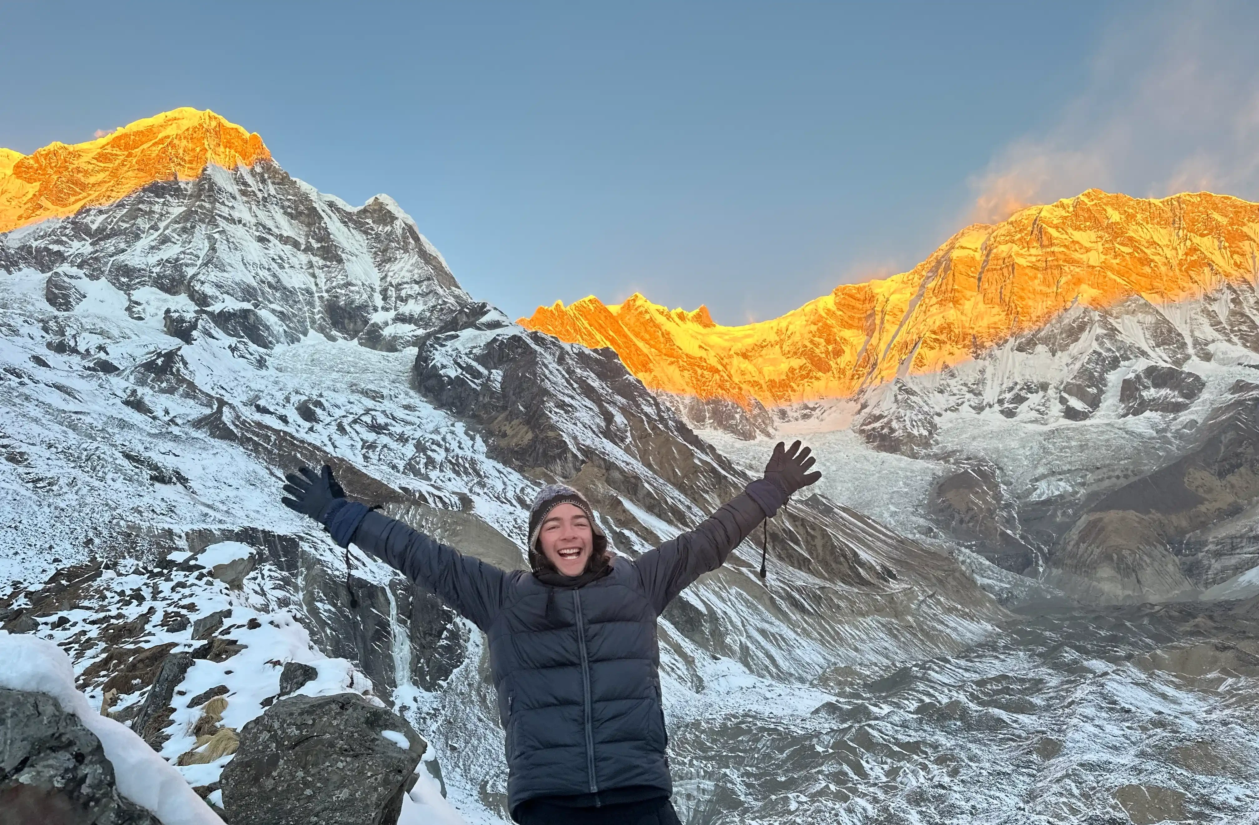 Sunrise bathes Annapurna Base Camp in Nepal in a golden glow, highlighting the majestic Himalayas. Experience this trek for yourself in 2024 - see costs now!